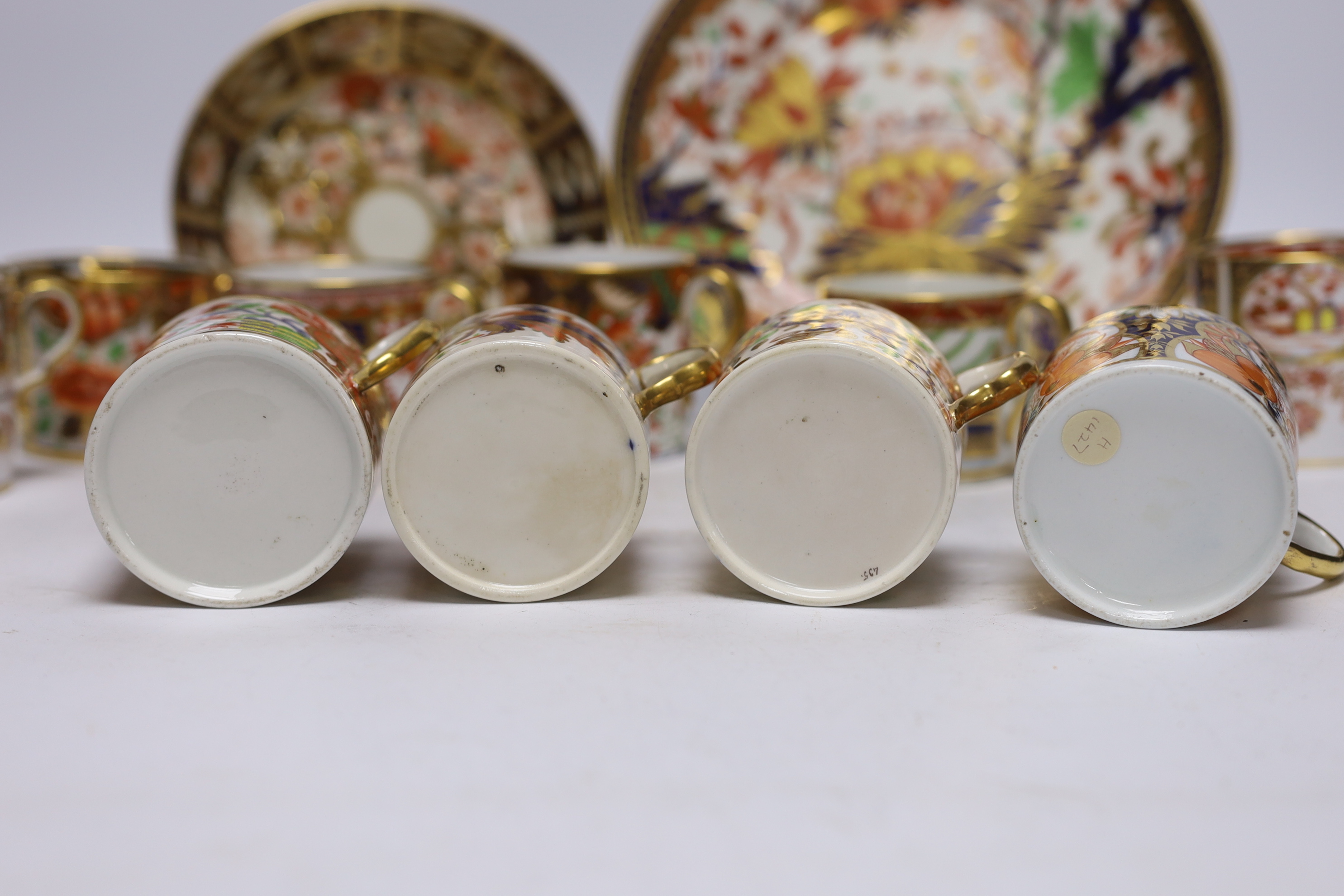 Ten 1800-1820 English porcelain coffee cans, including Imari pattern examples, one with matching saucer, together with a side plate (12)